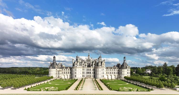 Een indrukwekkend kasteel met verzorgde tuinen en een blauwe lucht.