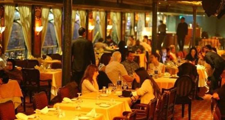 Zone de restauration dans un restaurant faiblement éclairé avec plusieurs clients assis aux tables.