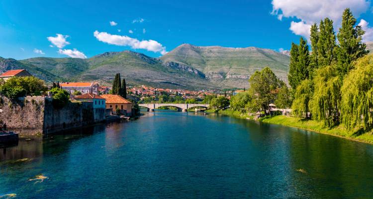 Río que atraviesa una ciudad con montañas al fondo.