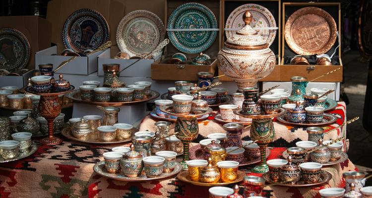 Exposición de elegantes juegos de café de cobre bosnio y cerámica en un puesto de mercado.