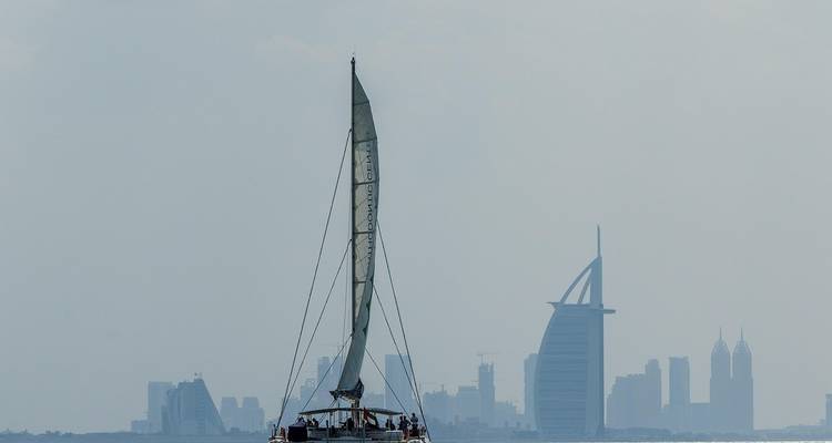 Sailboat on water with Dubai skyline in the background.