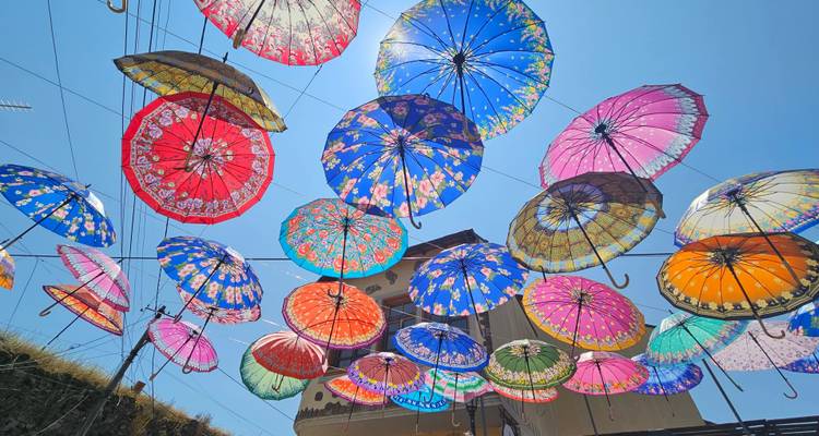 Colourful canopy of decorative umbrellas strung over a sunny Albanian street seen from below