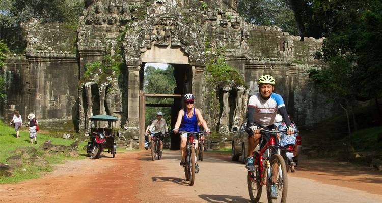 Cyclists riding near an ancient temple entrance.