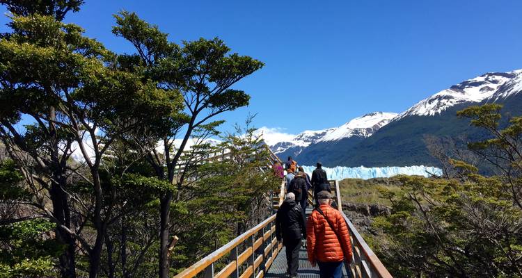 Des gens marchant sur une promenade avec une vue sur les montagnes et un glacier.
