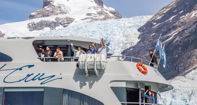 Des gens sur un bateau de croisière avec un glacier et une montagne en arrière-plan.