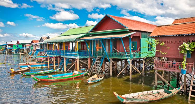 Kleurrijke paalwoningen langs een rivier met boten