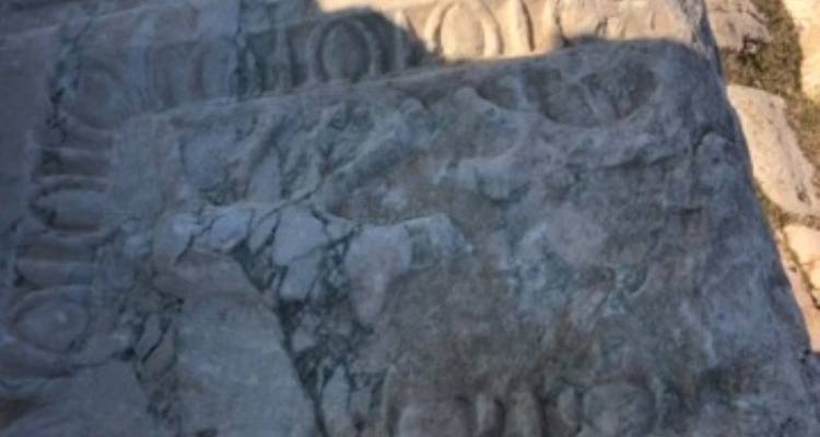 Weathered stone with carvings in low relief.