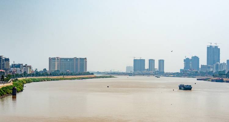 Un río ancho con edificios modernos bajo un cielo brumoso.