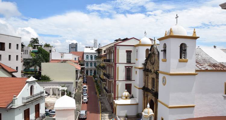 Stadtstraße mit historischen Gebäuden und einer Kirche unter blauem Himmel.