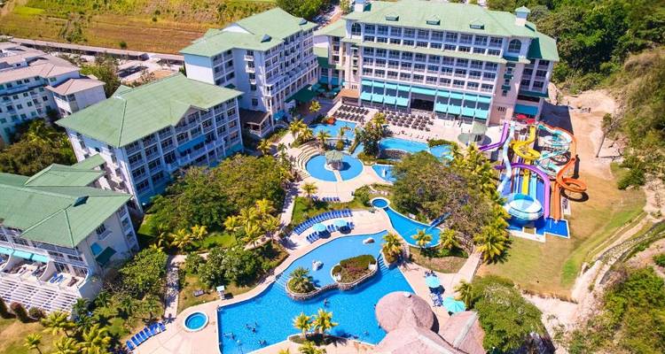 Luftaufnahme eines Resorts mit mehreren Schwimmbädern und üppigem Grün.