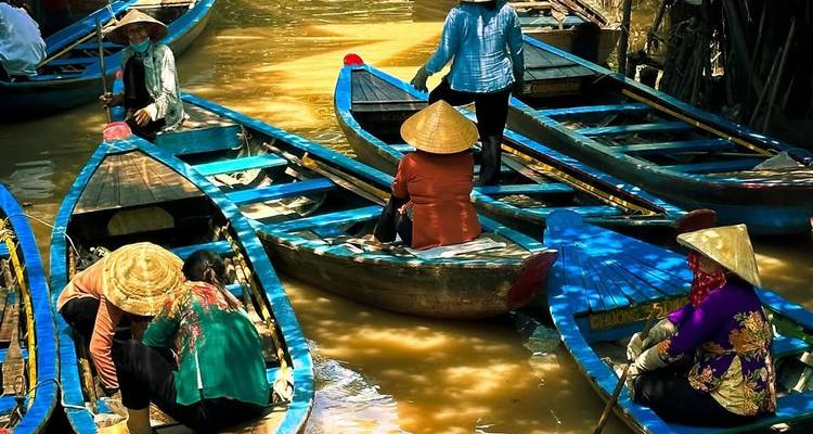 Multiple people paddling boats in a river surrounded by vegetation.
