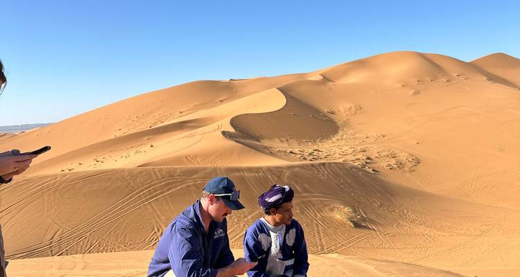 Deux personnes assises sur des dunes de sable, paysage désertique.