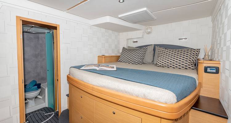 Cabine avec un lit double et un livre ouvert à l'intérieur d'un yacht.