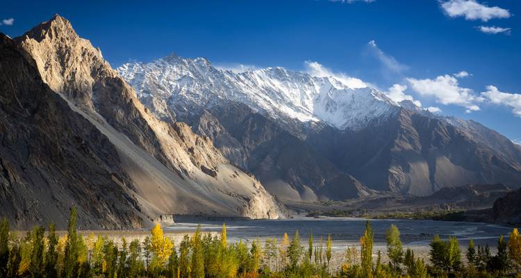 Spectacular snow-capped Karakoram peaks towering above colourful autumn forest and wide valley