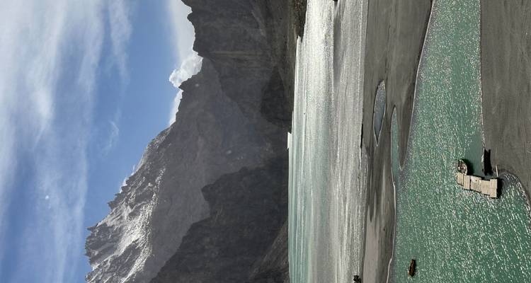 Lago turquesa con un muelle estrecho situado entre montañas rocosas empinadas bajo un cielo despejado