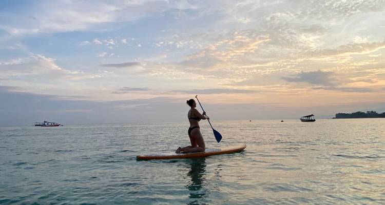 Personne faisant du paddle sur une mer calme au coucher du soleil.