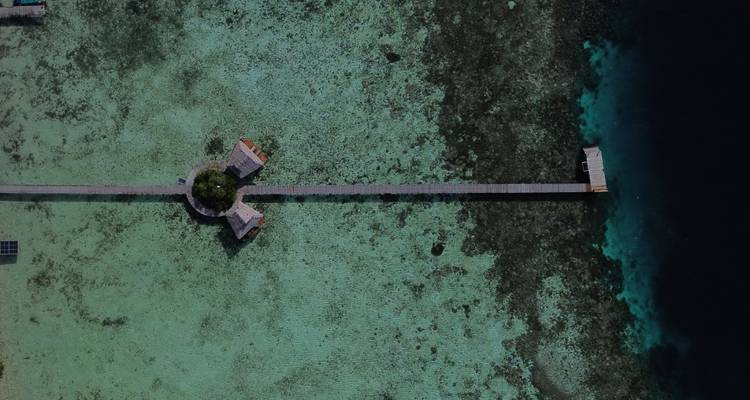 Vue aérienne d'une jetée et de structures sur pilotis dans une eau claire.