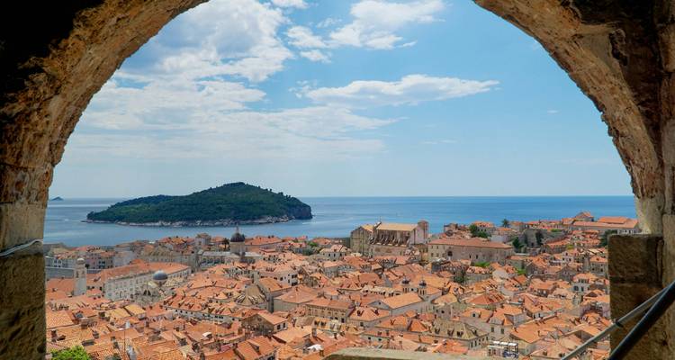 Vue d'une ville historique avec des toits en terre cuite et une île à proximité.