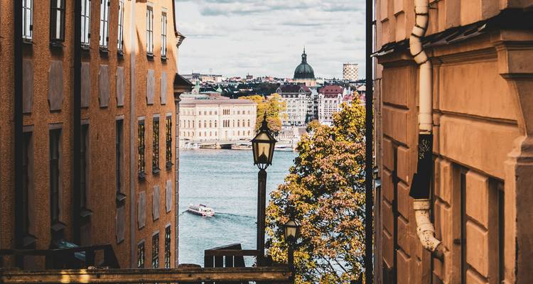Vue à travers une ruelle avec un paysage urbain et de l'eau au loin.
