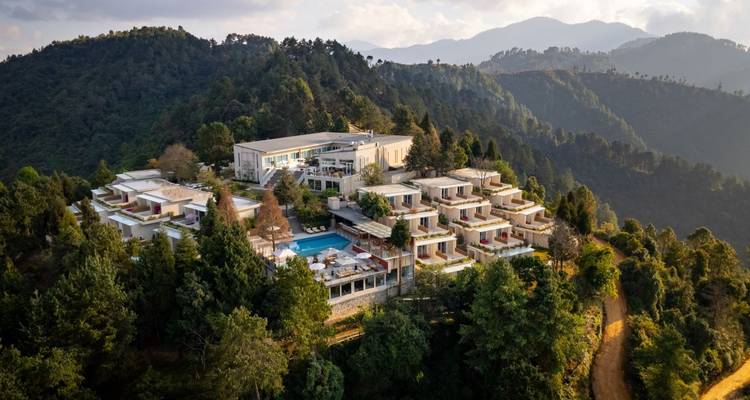 Resortcomplex op een beboste heuvel met een zwembad.