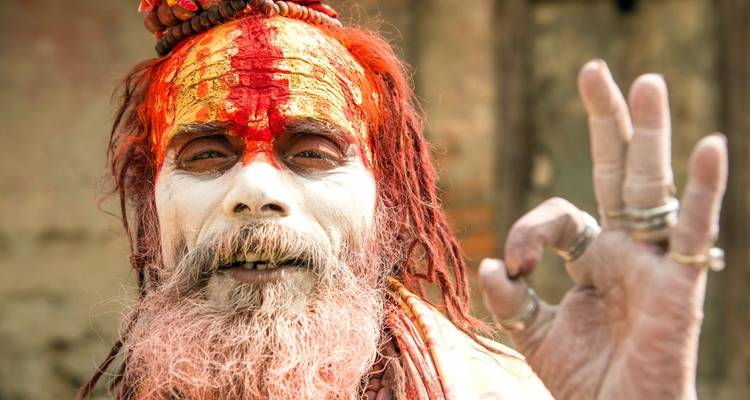 Man in kleurrijke traditionele kledij die een OK-teken maakt.