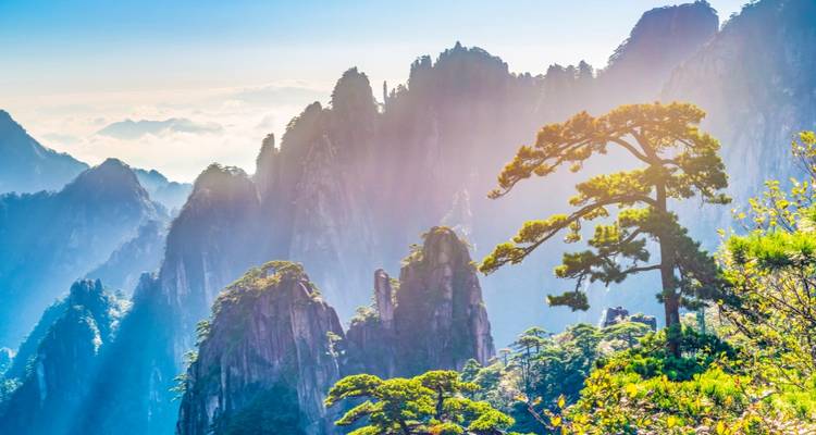 Picos de montaña cubiertos de niebla y luz solar.