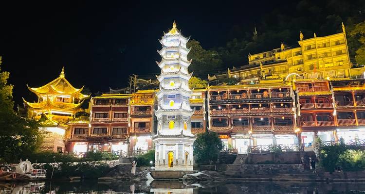 Pagode illuminée et bâtiments traditionnels la nuit.