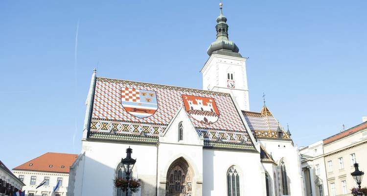 Historische kerk met sierlijke betegelde dak onder een heldere hemel.