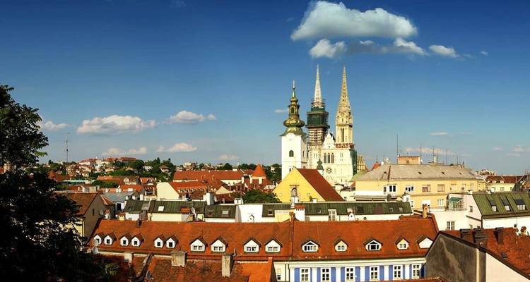 Skyline met prominente kerktorens en rode pannendaken.