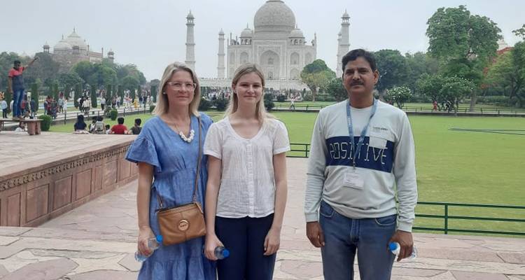 Trois personnes posant devant un grand mausolée en marbre blanc.
