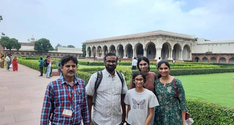 Cinq personnes posant devant un bâtiment historique avec des jardins.