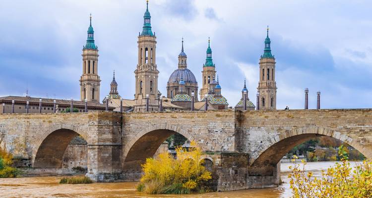 Close view of Basilica del Pilar in Zaragoza with a stone bridge and the river.
