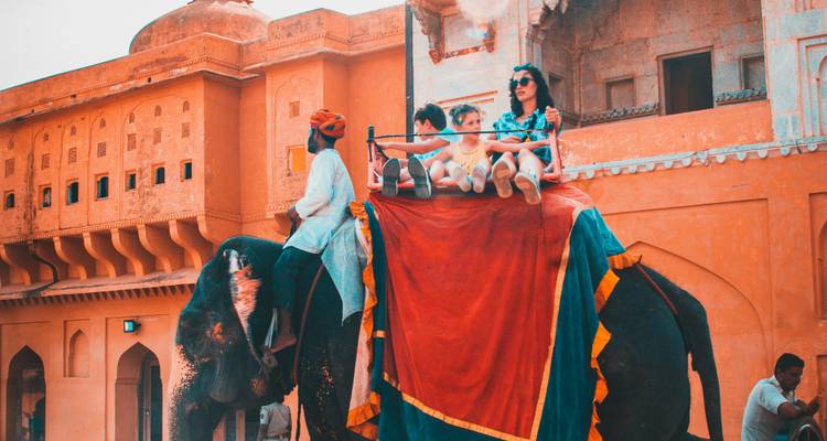 People riding an elephant at an architectural site.