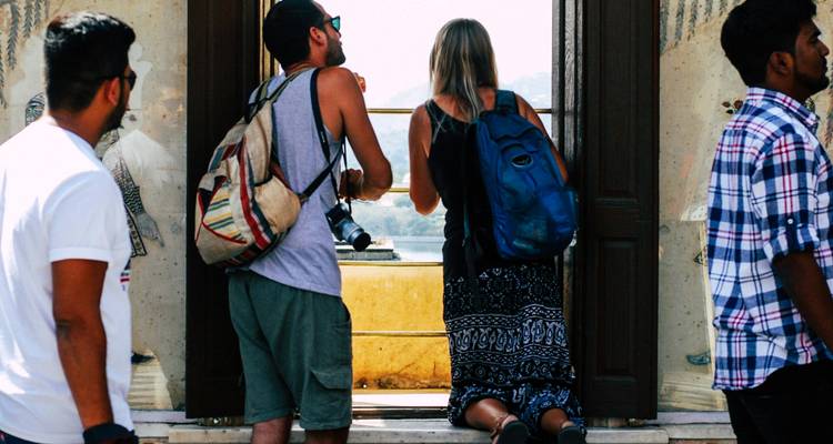 Group of people at a balcony overlooking cityscape.