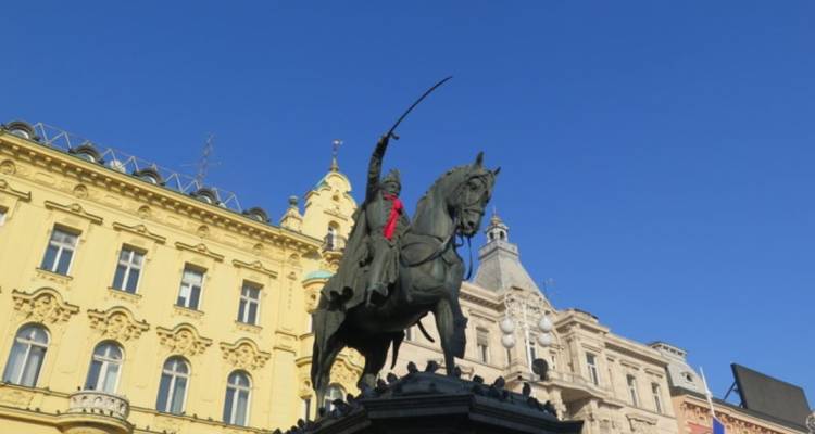 Statue équestre sur une place publique sous un ciel lumineux.