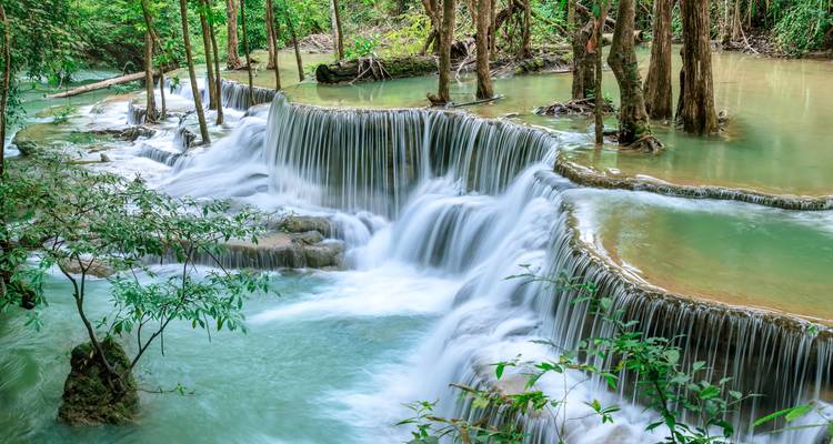 Waterfalls cascading over tiered rocks surrounded by lush greenery.