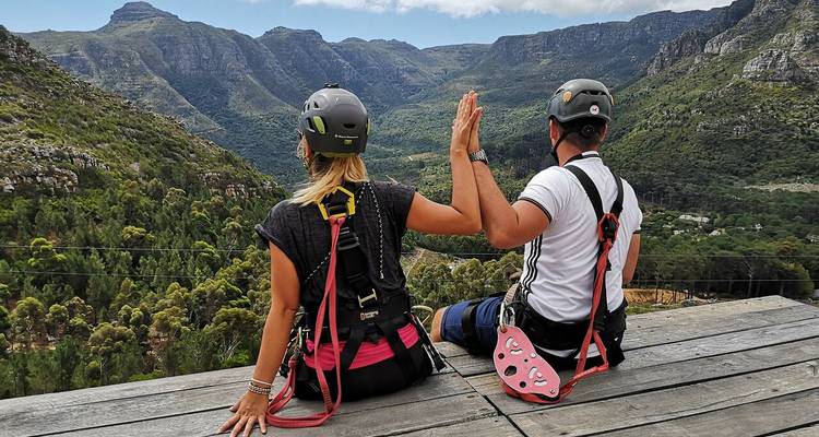 Zwei Personen mit Helmen sitzen mit malerischem Bergblick.