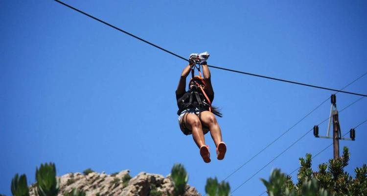 Person beim Ziplining vor blauem Himmelshintergrund.