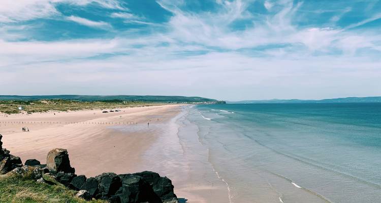 Lang zanderig strand met blauw water.