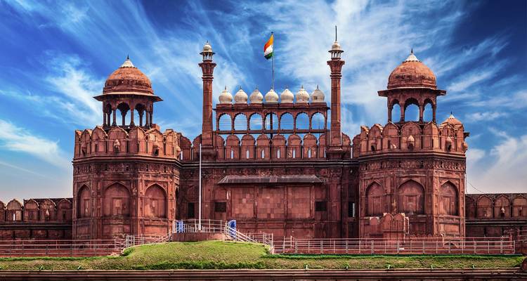 Los imponentes muros de arenisca roja y las cúpulas del Fuerte Rojo de Delhi bajo un cielo azul brillante.