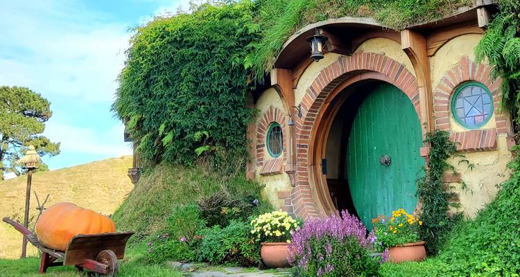 Encantadora casa estilo hobbit con una puerta verde y flores.