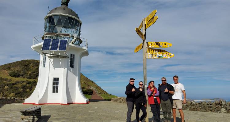 Turistas en un faro con señal de distancia.