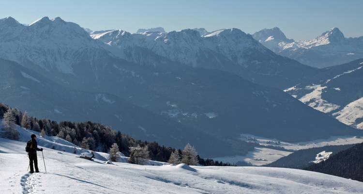 Lone skier amidst vast snow-covered mountains.