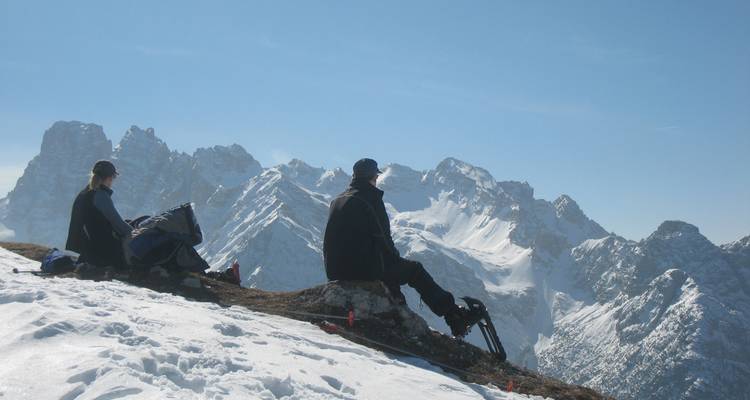 Two skiers resting with a snowy mountain range in the background.
