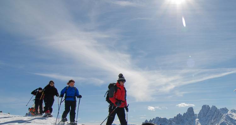 Group of skiers on a snowy mountain with a bright sun above.