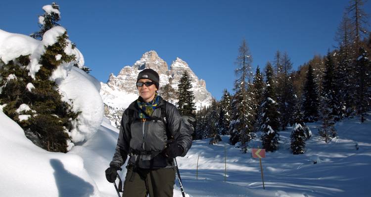 Skier posing in front of snow-covered trees and mountains.