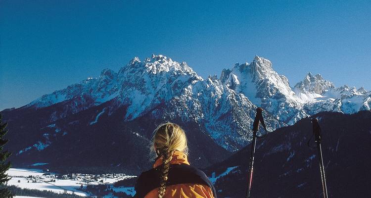 Woman skier looking towards snow-capped mountains.