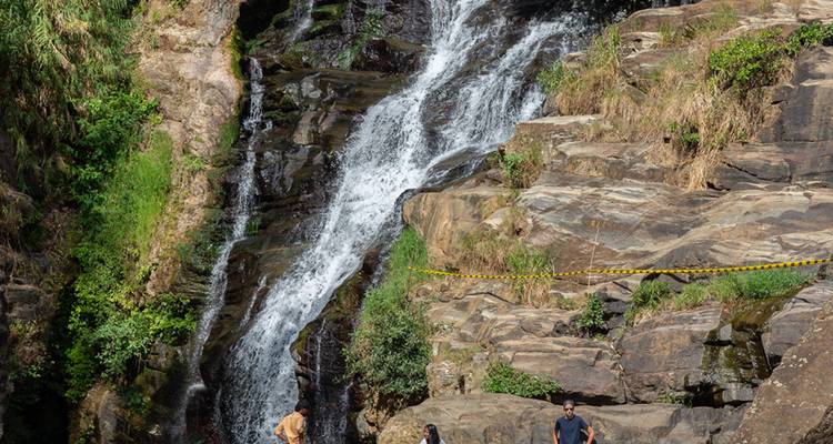 Mensen bij een waterval omringd door rotsen.