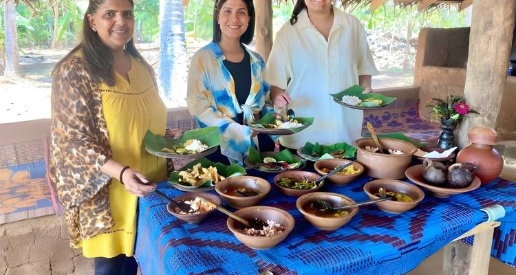 Drie mensen die een traditionele maaltijd presenteren met gerechten op een tafel.