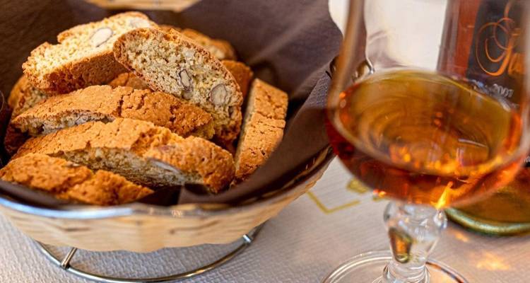 Un panier de biscotti et un verre de vin doux.